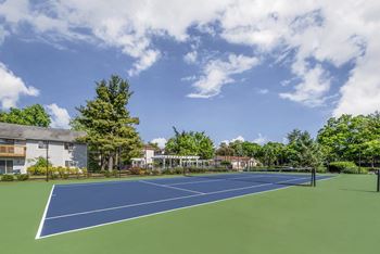 A tennis court surrounded by trees and buildings.
